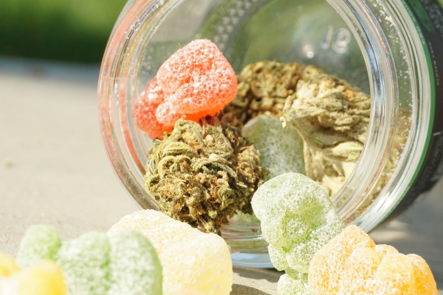 Gummies and cannabis flower spilling out of mason jar