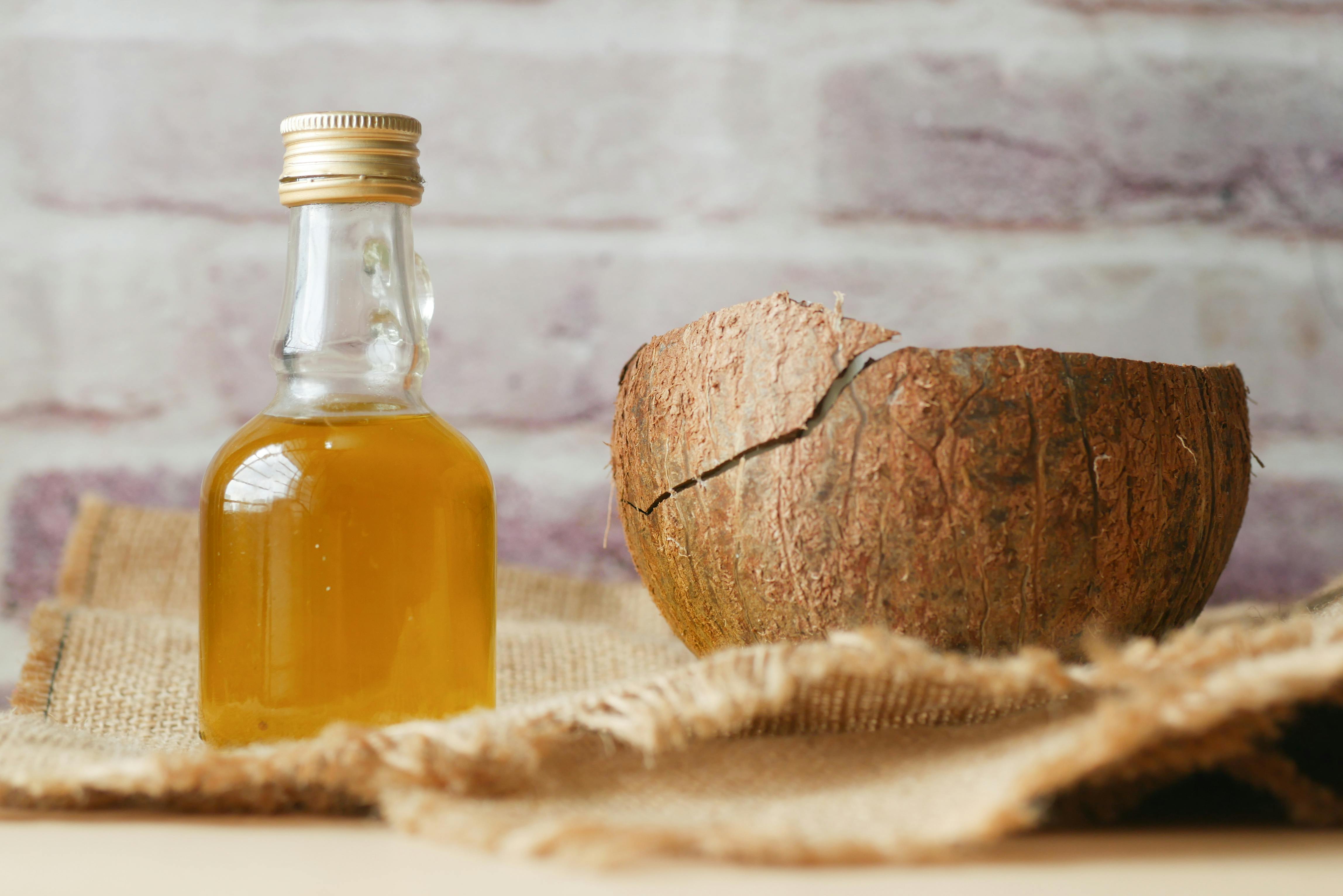 Bottle of infused coconut oil next to half a coconut